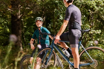 Male cyclists chill on gravel bikes in sunny forest