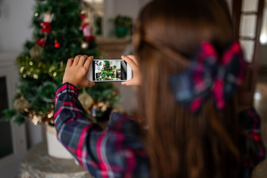 girl taking a picture of the christmas tree at home