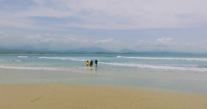 Grupo de personas entrando al mar para surfear. video dolly in desde dron video 4k. concepto turismo y viajes