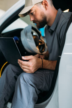 Man Working in Garage, Using Laptop for Diagnostic 