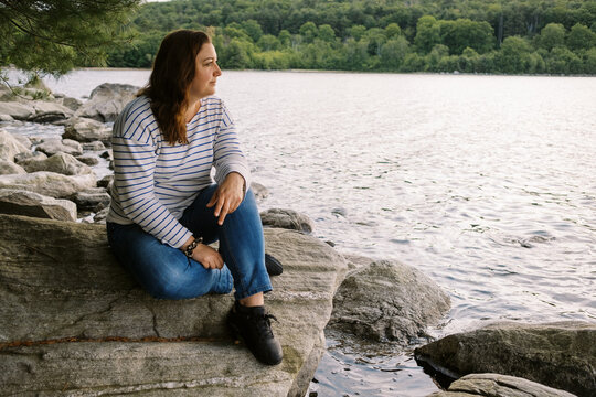 woman sitting on rock by a lake