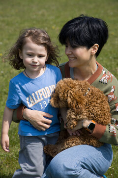 Woman with a poodle puppy and a little boy outdoor 