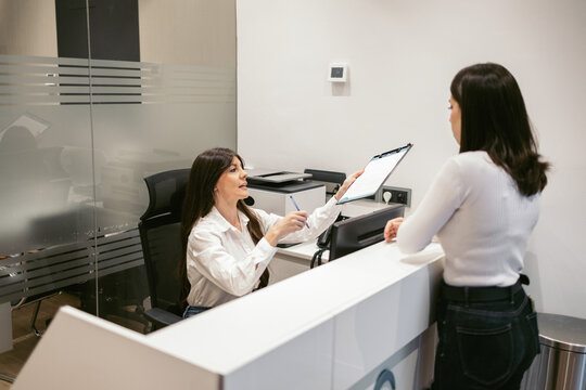 Receptionist of a clinic giving a form to a client