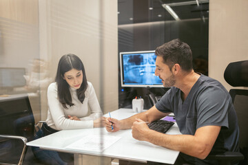 Dentist diagnosing a female client and offering her dental treatment