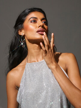 Tall, slender woman in party outfit touching her lips