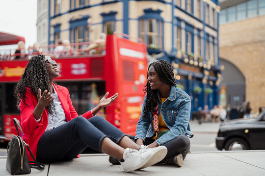 Women sitting on a bench in the city and having fun