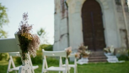 Chairs decorated for a wedding standing in front of the church