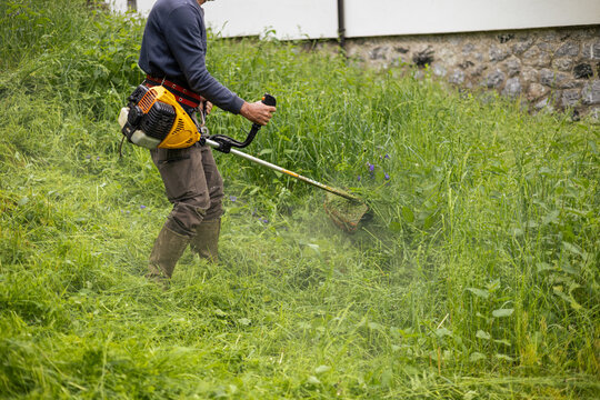 Man mows with a motor trimmer