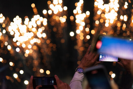 Unrecognizable people recording video of fireworks with cell phone