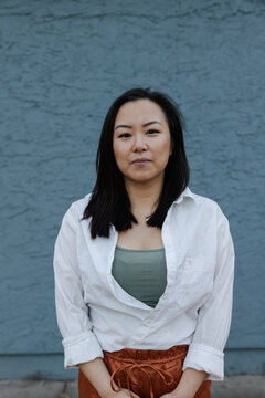 Serious portrait of woman near blue wall.