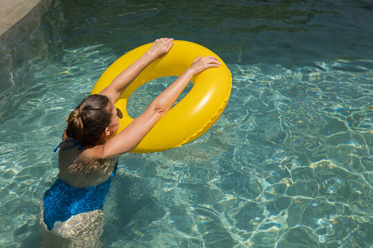 Woman play with a yellow inflatable in blue pool on summer