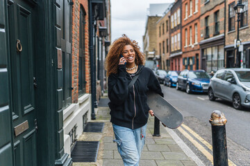 Smiling woman with skateboard walking on street
