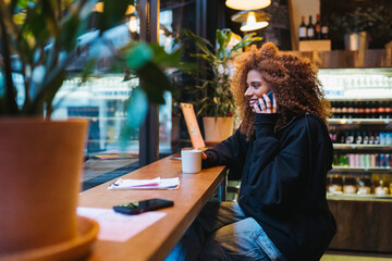 Cheerful woman with smartphone and coffee in cafe