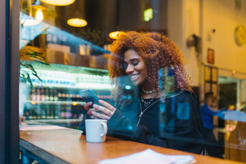 Laughing woman using smartphone in cafe