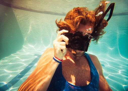 Man taking pictures under pool water