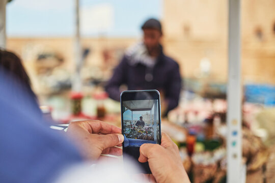 Close-up detail of a tourist taking a photo of a Moroccan fisherman