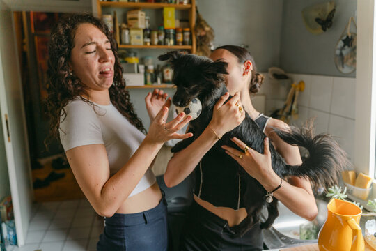 woman holding her dog., friend playing with dog disgusted by saliva 
