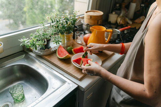hands of mature woman slicing watermelon in her kitchen