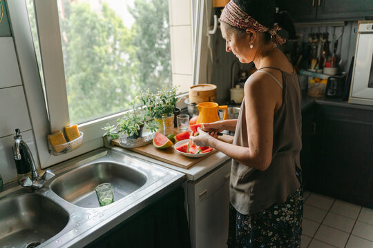 woman slicing watermelon in her kitchen