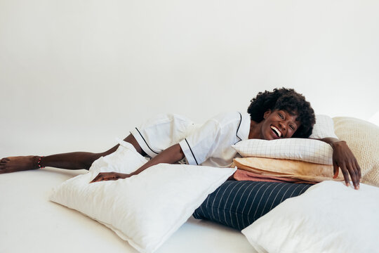 Woman in Pajamas Lying on Pillows and Laughing
