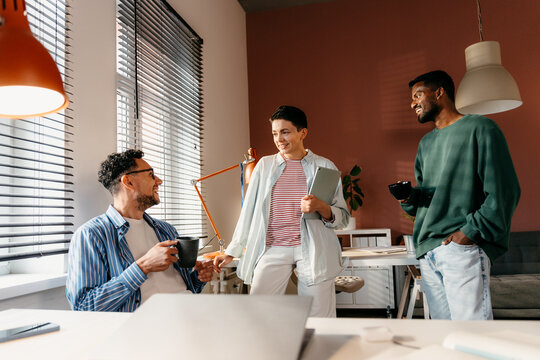 Three colleagues laugh on a break in the office
