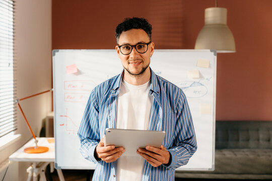 A man with a tablet in his hands smiles looking at the camera