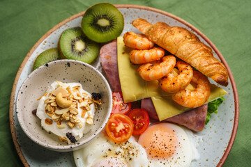 Breakfast sandwiches, croissants, ham, cheese, shrimp, fried eggs and yogurt.