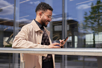 A cheerful businessman reads good news on a smartphone