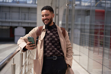 A cheerful businessman reads good news on a smartphone