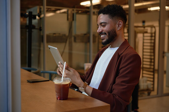 A Man Uses A Tablet In A Cafe