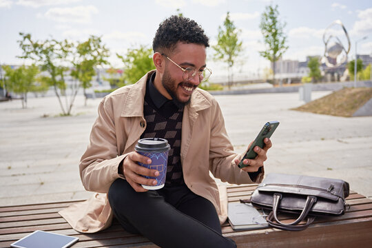A cheerful businessman reads good news on a smartphone
