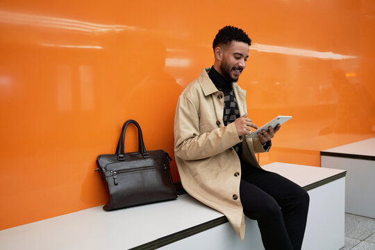 A young businessman uses a tablet at a subway station