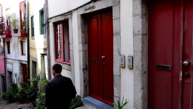 Red doors and windows with a man walking through Rua da Pena Ventosa in Porto, Portugal