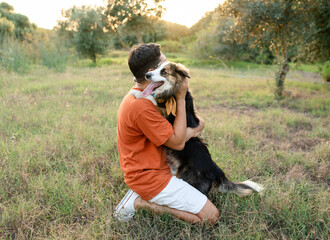 man hugging his dog in the field