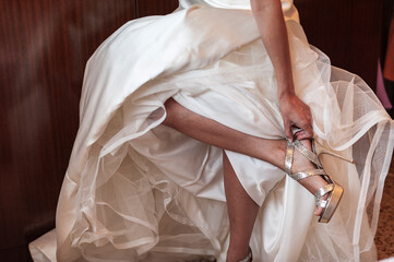 Bride getting dressed tying her bridal shoes