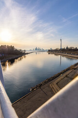 Fototapeta premium Humber Bay Shores Park skyline and a windmill reflecting in Lake Ontario and the Ontario Place West Channel at sunset