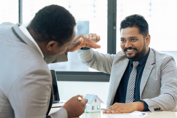 Real estate agent with House model is talking to clients about buying home insurance
