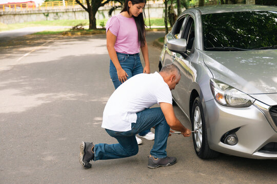 Teacher teaches young woman how to change a tire