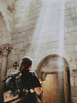 Sunlight from a window falls on a young tourist woman in old church