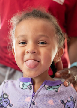 Closeup portrait of a preschooler wagging her tongue.