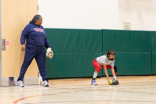 Woman training a child in fielding grounders for softball