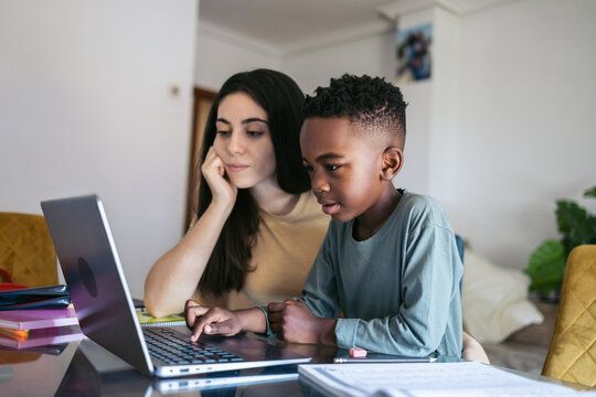 Babysitter helping little boy to do homework at home