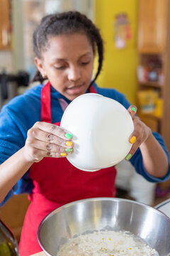 Tween pouring the contents of a small bowl into a bigger one.