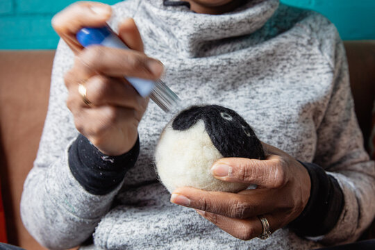 Woman using a multi needled felting tool to dry felt some wool