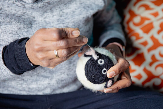 Woman holding a cute handmade sheep dryer ball as she felts it