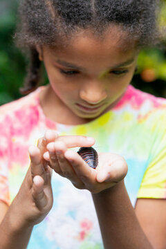 Child holding and fearlessly petting a large cockroach 