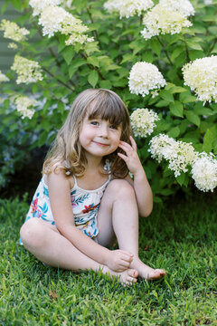 toddler girl in front yard among blooming panicle hydrangeas