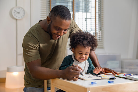 Friendly father helping cute little son with homework