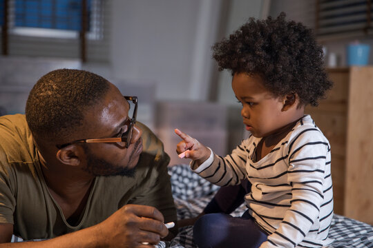 Father listening to his little son speaking while pointing finger