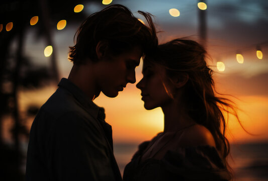 silhouette of a young couple sharing a tender moment by the ocean at sunset. Ideal for romantic themes.